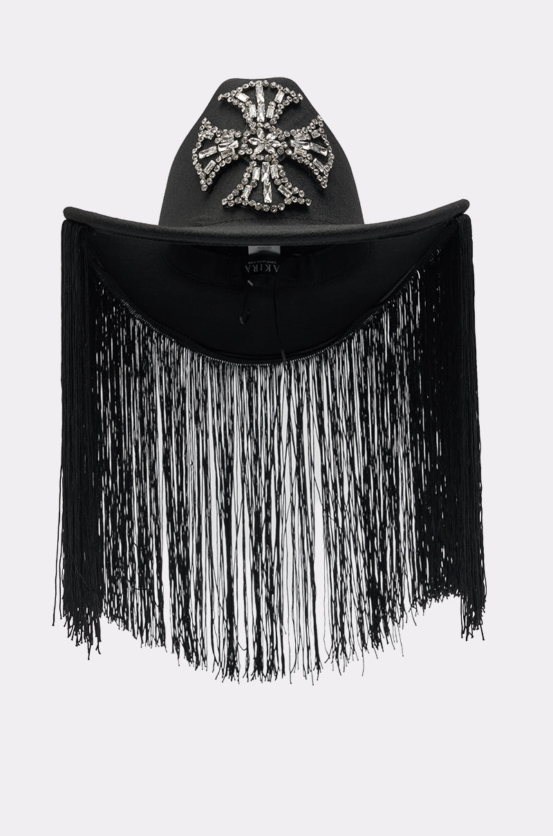The CALL MY HATERS FRINGE BRIM HAT is a black cowboy hat with a bold rhinestone cross on the front and long fringe trim draping elegantly from the brim over the face. 2