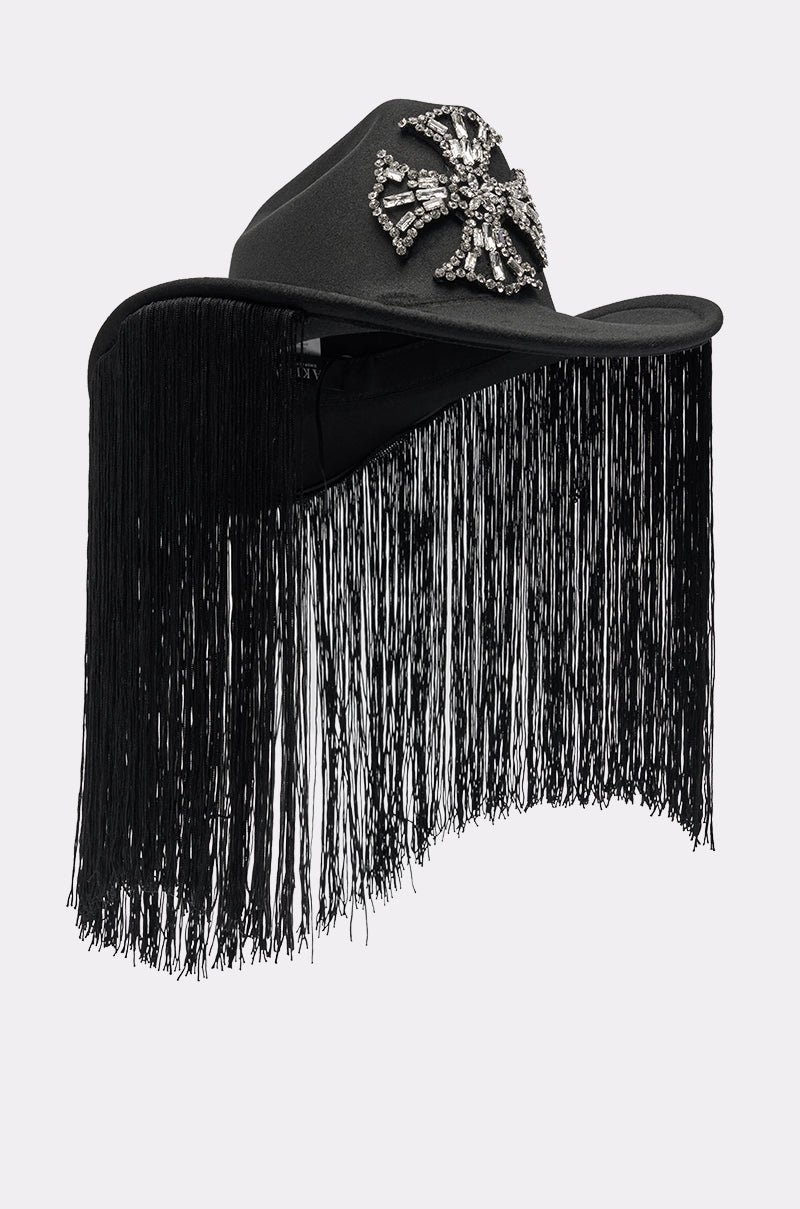 The CALL MY HATERS FRINGE BRIM HAT is a black cowboy hat with a rhinestone cross on the front and long black fringe draping from the brim to stylishly cover the face. 3