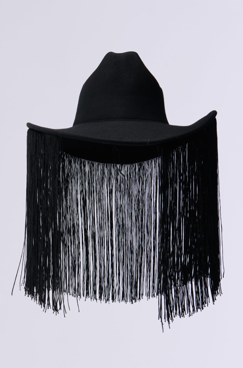 The BE SO FR FRINGE BRIM HAT is a stylish black accessory featuring a wide brim and embellished with long black fringe, beautifully standing out against a plain light background. 3