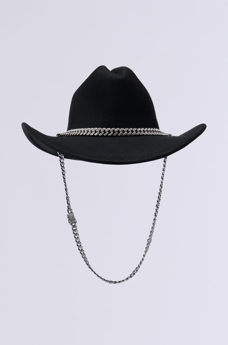 The LET IT RIDE CHAIN COWBOY HAT features a wide-brimmed black design, accentuated by a rhinestone-embellished chain circling the crown and a dangling chain chin strap, making it an ideal Western accessory set against a plain light gray background. 2