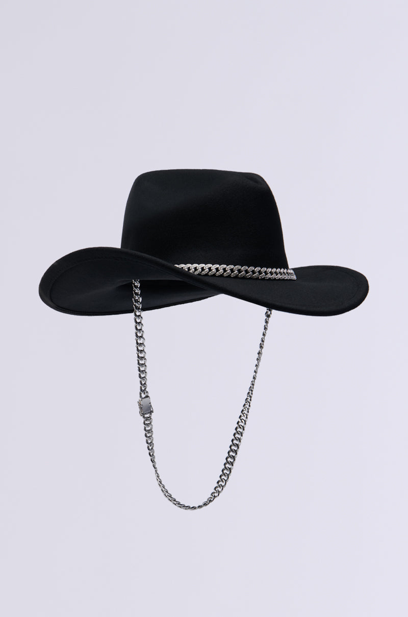 The LET IT RIDE CHAIN COWBOY HAT is a striking Western accessory that stands out with its unique flair. It features a wide-brimmed black design, adorned with a rhinestone-embellished silver chain as both a decorative band and chin strap, set against a light grey background. 3