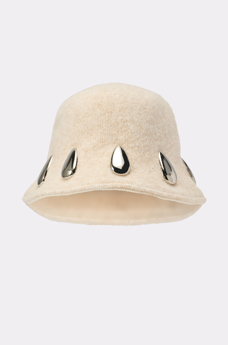 The OUTSIDE METAL DETAIL BUCKET HAT is a slouchy beige bucket hat featuring large shiny silver teardrop-shaped embellishments around the brim, shown against a plain light background. 2