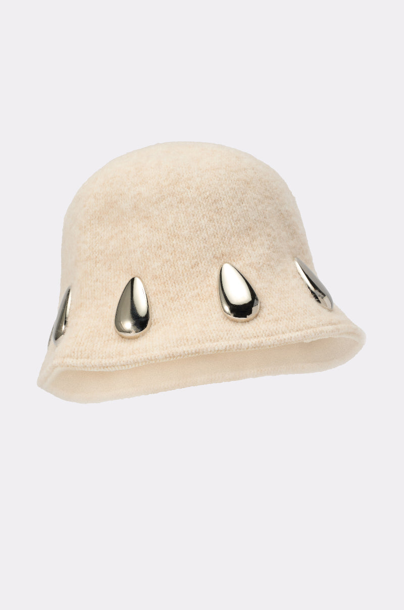 The OUTSIDE METAL DETAIL BUCKET HAT is a beige, textured slouchy bucket hat adorned with evenly spaced shiny silver teardrop-shaped metal details around the brim. 3
