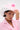 Wearing the TO THE RACES FLOWER HAT, a person with short dark hair, subtle makeup, and a nose ring tilts the white cowboy hat adorned with pink flowers and looks confidently at the camera against a plain background.