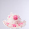 The TO THE RACES FLOWER HAT from AKIRA Label is a white wide-brim hat adorned with pink fabric flowers and delicate, translucent petals, shown against a plain light background.