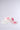 The TO THE RACES FLOWER HAT, inspired by the AKIRA Label aesthetic, features pink and light pink fabric flowers on a white base and is photographed against a plain light gray background.