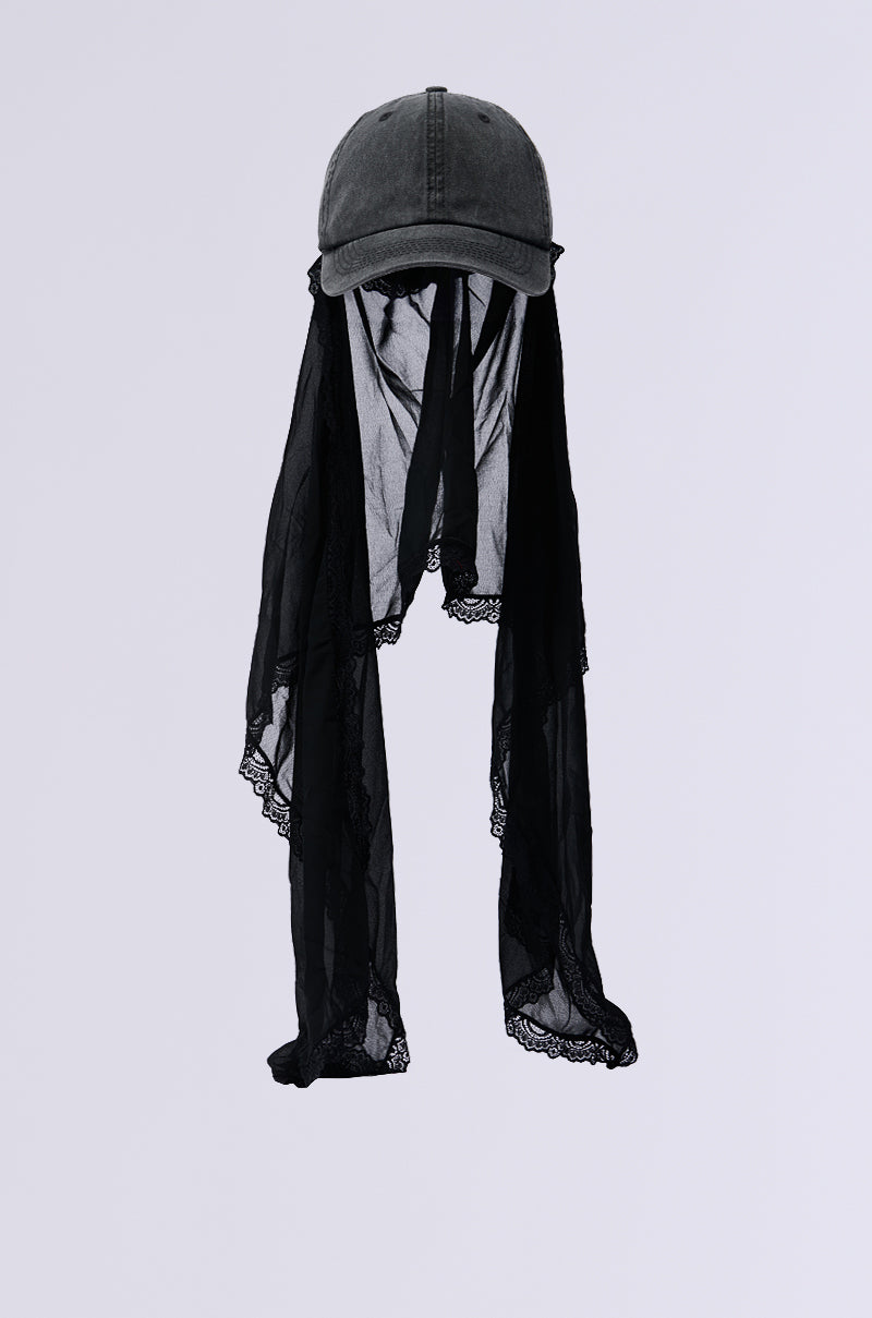 Introducing the TRINA VEIL SNAPBACK, a black baseball cap featuring long, sheer lace fabric that drapes gracefully. The intricate lace edges provide a distinctive flair to this snapback, creating an elegant contrast against its simple base. 3