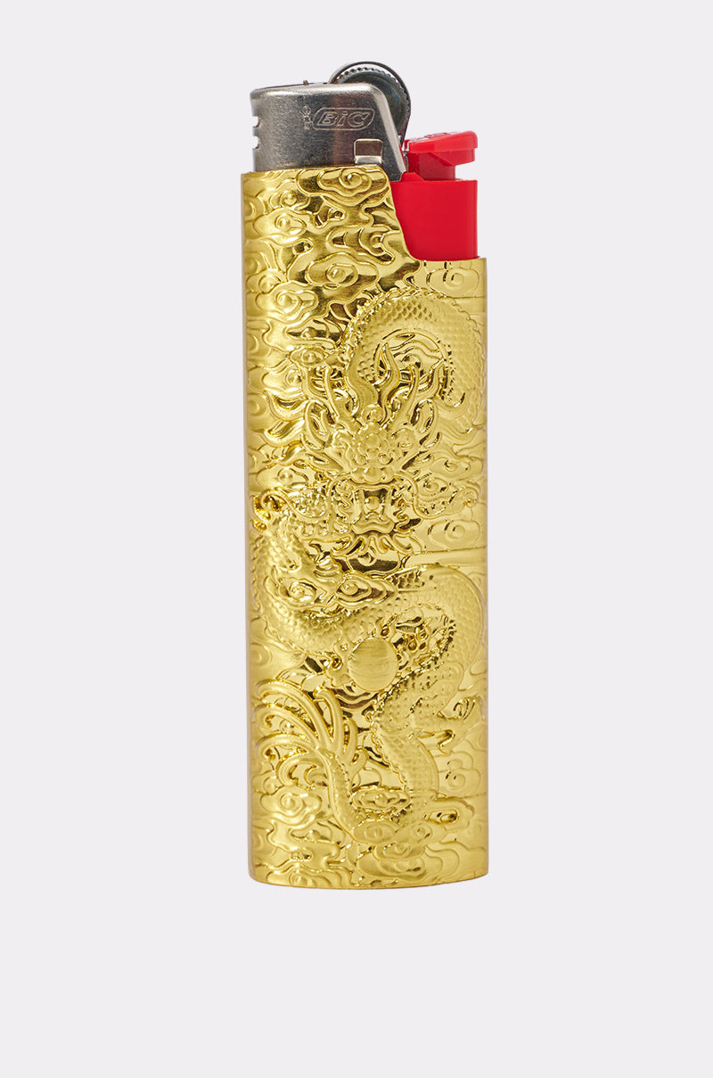 The GOLDEN ERA LIGHTER CASE, featuring a gold-tone finish with an embossed dragon motif and a bold red thumb lever, is showcased against a clean light background. This exquisite case brings an air of elegance and mystique to any collection.