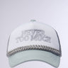 The AND THATS THAT TRUCKER HAT is a light-colored cap featuring the phrase "NEVER TOO MUCH" embroidered on the front. It includes a woven chain detail along the brim and mesh paneling designed for breathability, while an adjustable snapback closure provides a perfect fit. The background transitions smoothly from white to light gray.