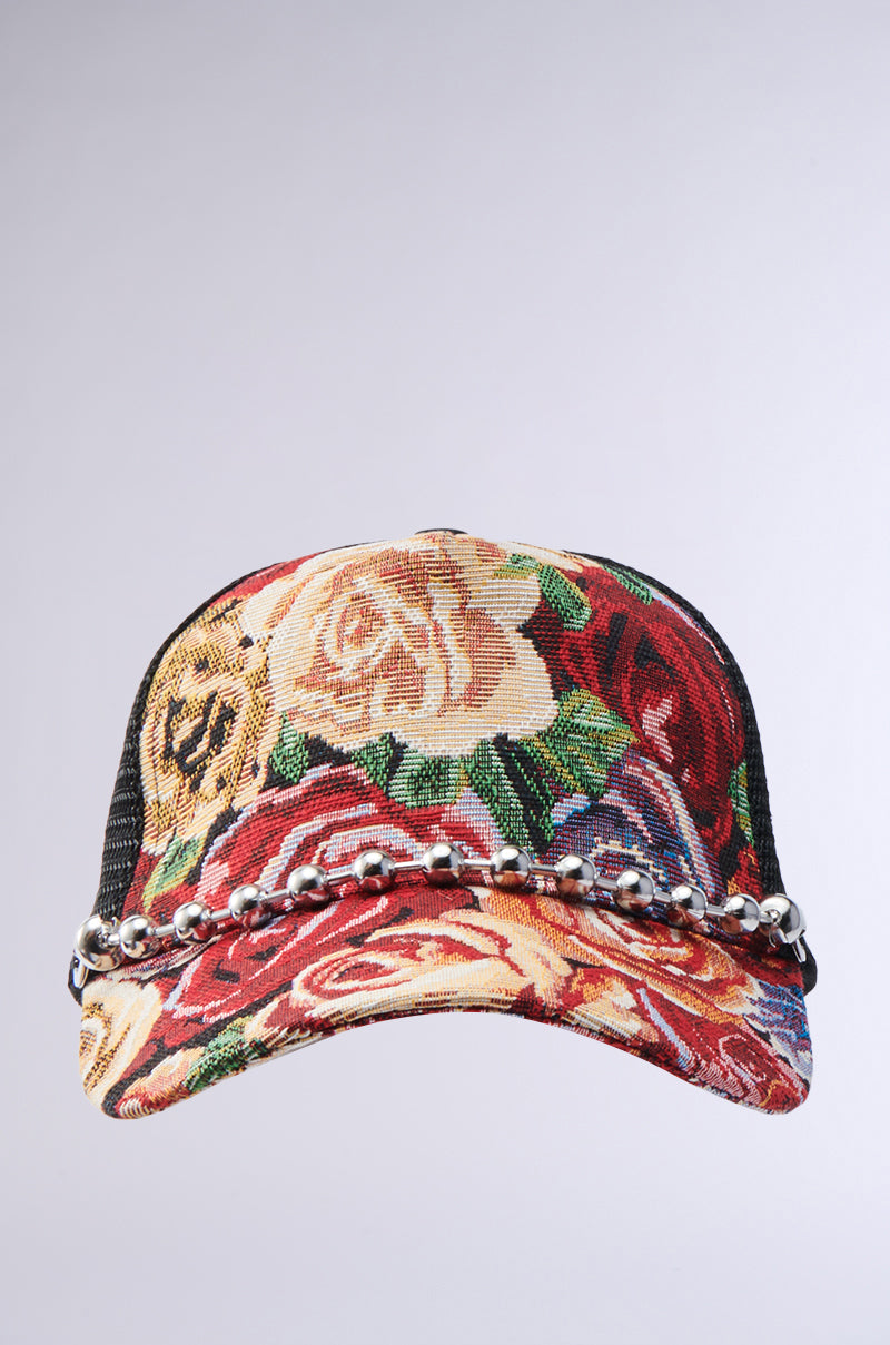 The ROSES ARE RED TAPESTRY HAT is a baseball cap featuring a vibrant floral tapestry design, black mesh back, and a row of metallic beads across the front of the brim.