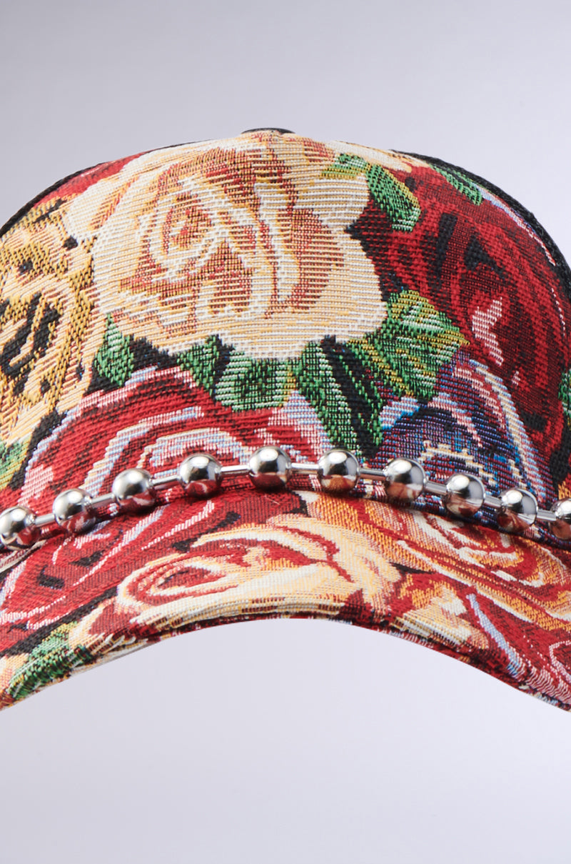 A close-up of the ROSES ARE RED TAPESTRY HAT, featuring a vibrant floral pattern, embroidered rose design, and a row of metallic beads across the brim.