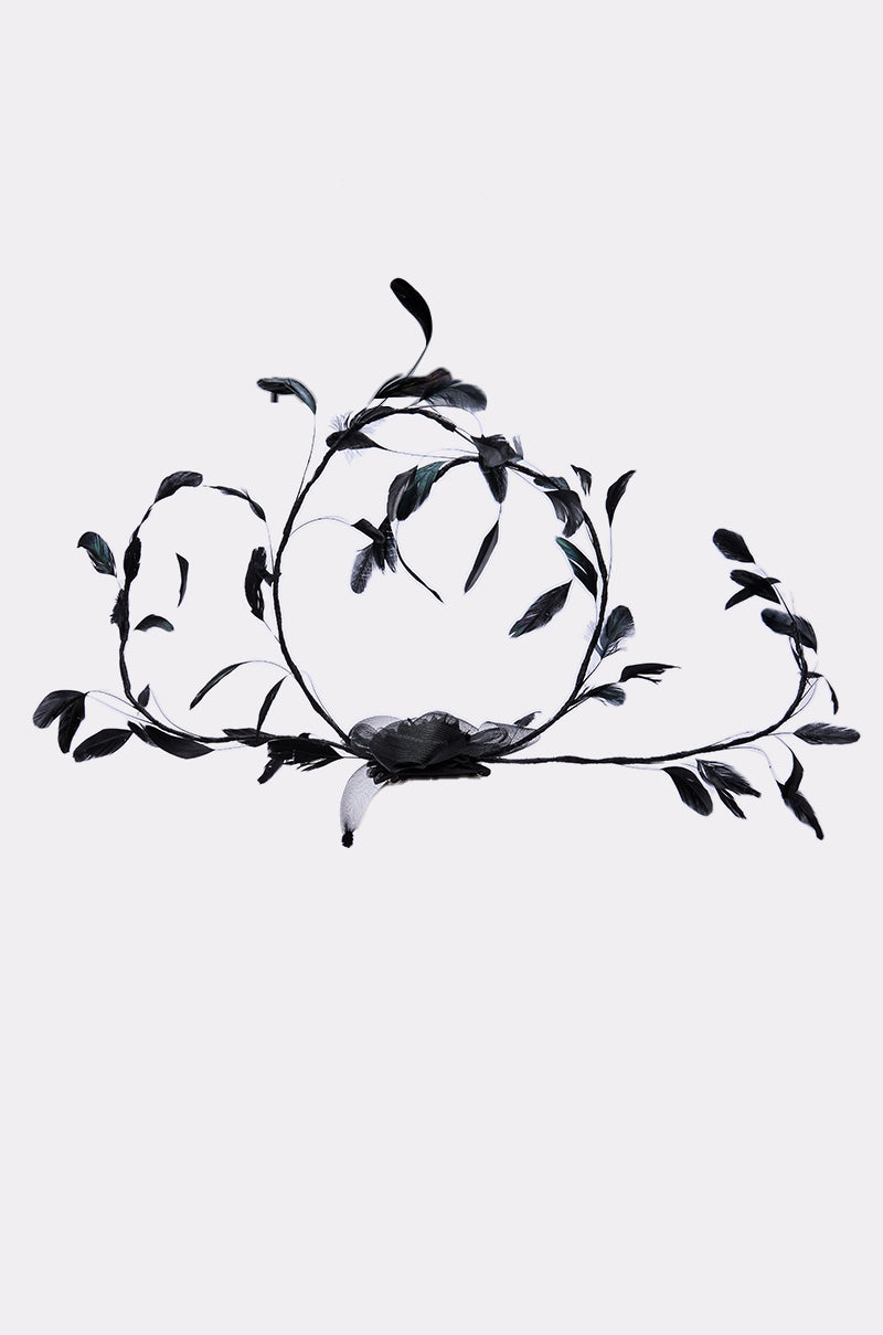 The IN YOUR DREAMS CLIP ON HAT is a chic black accessory adorned with detailed leaves and vines in an elegant swirling pattern, ideal for adding a subtle statement to any outfit.