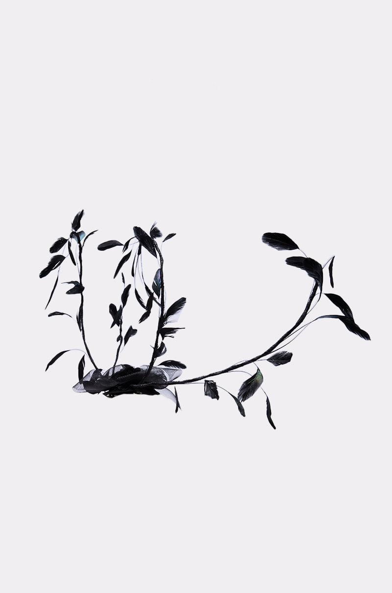 A single dark-leaved vine stretches across a light background, its minimal silhouette echoing the refined simplicity of the IN YOUR DREAMS CLIP ON HAT in fashion accessories.
