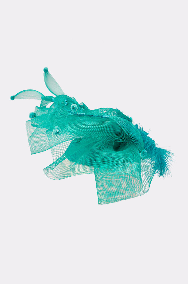 The INTO THE GARDEN BLOOMING HAT is a turquoise fascinator with layered mesh, decorative feathers, and small bead accents—an elegant formal hat shown on a plain white background. 2
