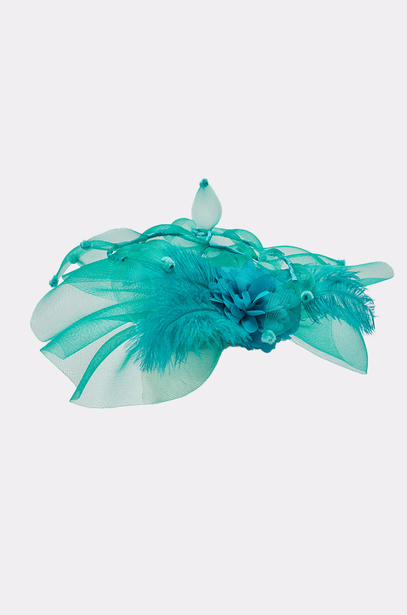 The INTO THE GARDEN BLOOMING HAT is a turquoise fascinator with mesh loops, decorative feathers, and a flower with a teardrop-shaped bead, creating an elegant wedding accessory against a white background. 3
