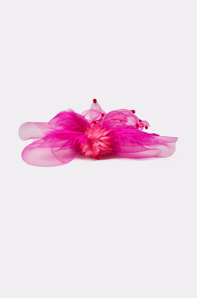 The RIRI HEADPIECE features a bright pink design with flowing sheer ribbon, large feathers, a fabric flower center, and small pom-pom accents—making it the perfect festival accessory against a plain light background. 3