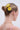 A woman with blonde hair in a neat bun, styled with the LIFE GIVES YOU LEMONS HAIR CLIP SET—lemon and orange-shaped barrettes—wears a gold chain necklace and pink strap top, seen from the back against a plain light background.