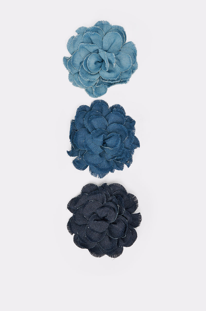 The DENIM ERA BROOCH features three denim flower-shaped brooches in light, medium, and dark blue arranged vertically on a white background—a charming statement accessory for any outfit. 6