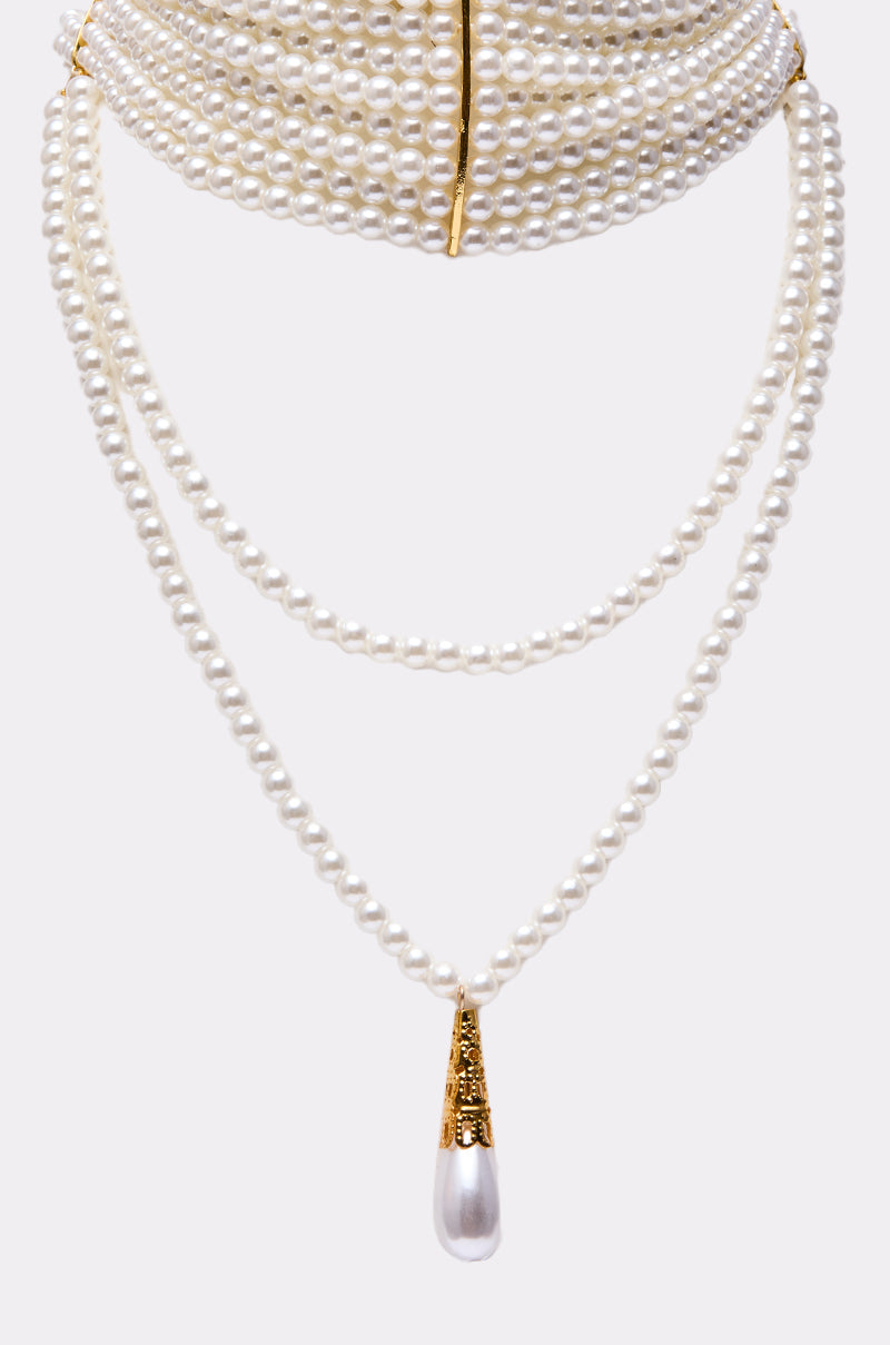 The VERSAILLES NECKLACE is a striking accessory featuring layered faux pearls, gold accents, and a gold-capped teardrop pearl pendant, displayed on a plain white background. 4