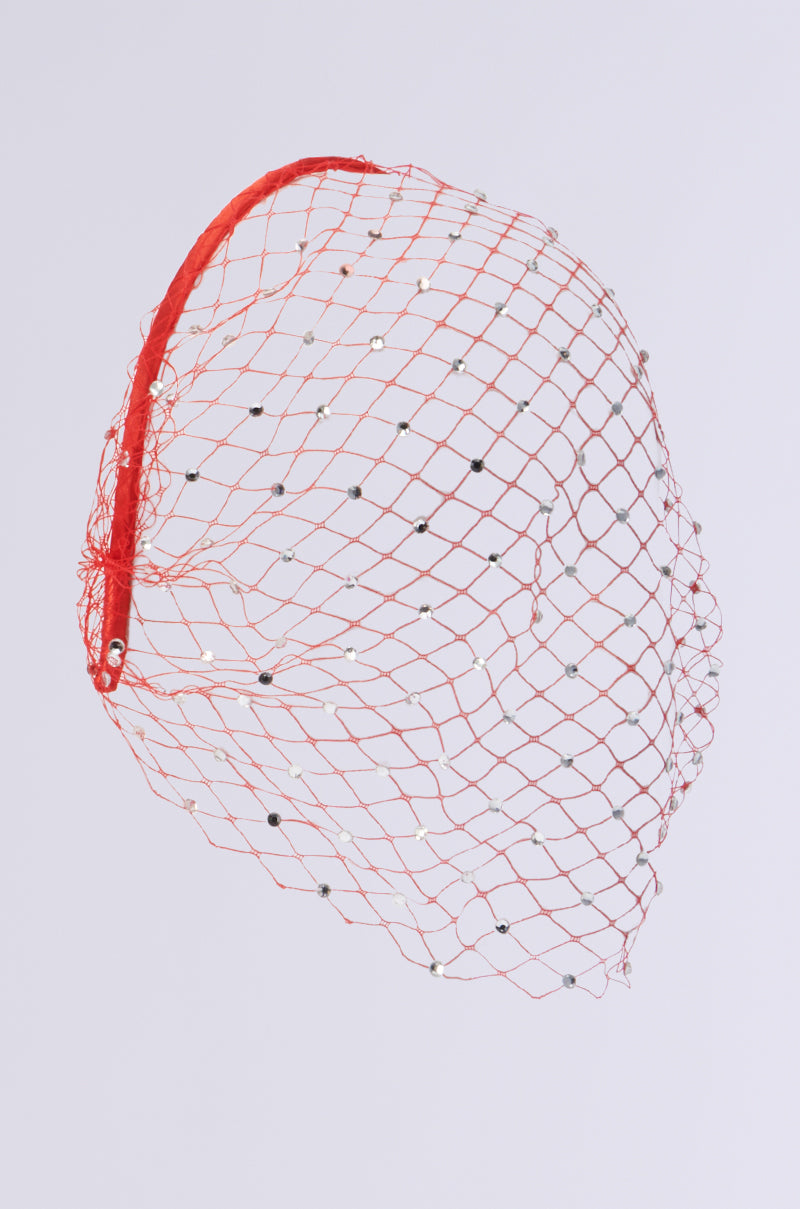 The I SEE FIRE RHINESTONE HEADBAND, crafted by AKIRA Label, features a red fishnet mesh veil adorned with small silver sequins that sparkle under the light. It is designed with a curved band for wearing, and its domed netting is elegantly displayed against a plain background. 4
