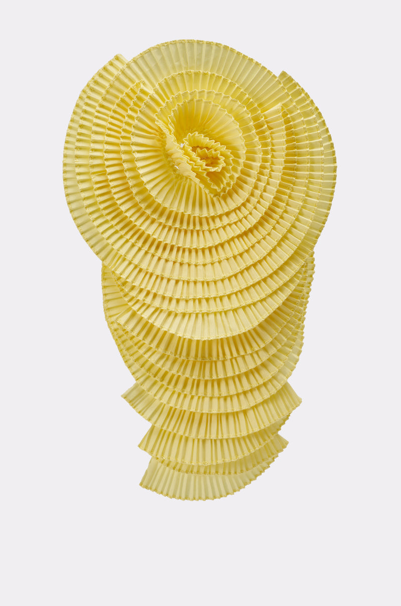 The IN THE GARDEN OVERSIZED BROOCH features stacked, overlapping yellow paper liners in a spiral, flower-like design set against a plain white background. 4