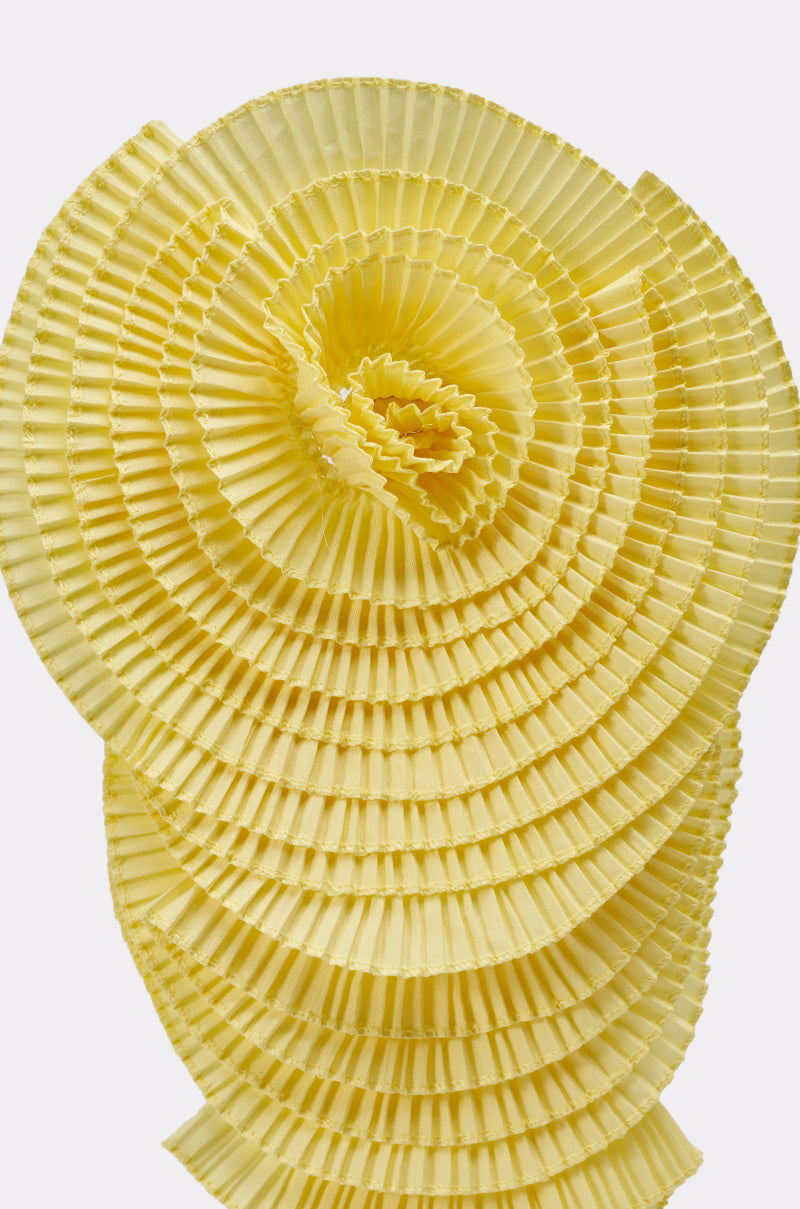 A close-up of the IN THE GARDEN OVERSIZED BROOCH shows its yellow, fluted layers arranged in a spiral, creating a textured, eye-catching effect. 6