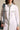 A woman wears the LEILA OVERSIZED WHITE MULTI BUTTON UP, featuring light-washed denim trim on the collar, cuffs, pocket flaps, and button placket. She carries a denim bag over her shoulder while her face is partially out of frame.
