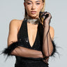 A person with braided hair wears a glamorous black sequin dress and Featherington Gloves, which feature exquisite feather trim detailing. A sparkling choker necklace enhances the elegance as they pose confidently against a light background, holding part of the Featherington Glove near their face.