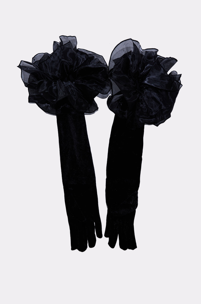 AT THE GALA VELVET GLOVES: Opera-length black velvet gloves with large ruffled organza flower accents at the wrists, shown on a light background. 4