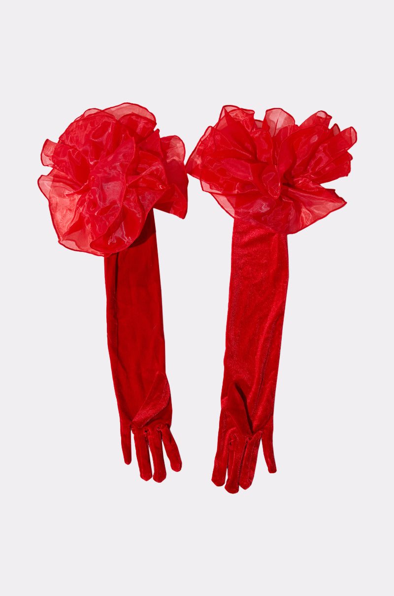 AT THE GALA VELVET GLOVES: A striking pair of red velvet opera gloves, featuring bold ruffled organza flower accents at the top, displayed on a plain light background. 2