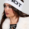 A woman with long brown hair wears the SO HOT RIBBED HEADBAND, pairing it with a black top and a fur jacket that features a decorative bowtie. Her bold makeup, including smoky eyeshadow and glossy lips, completes her look for any chilly outing.