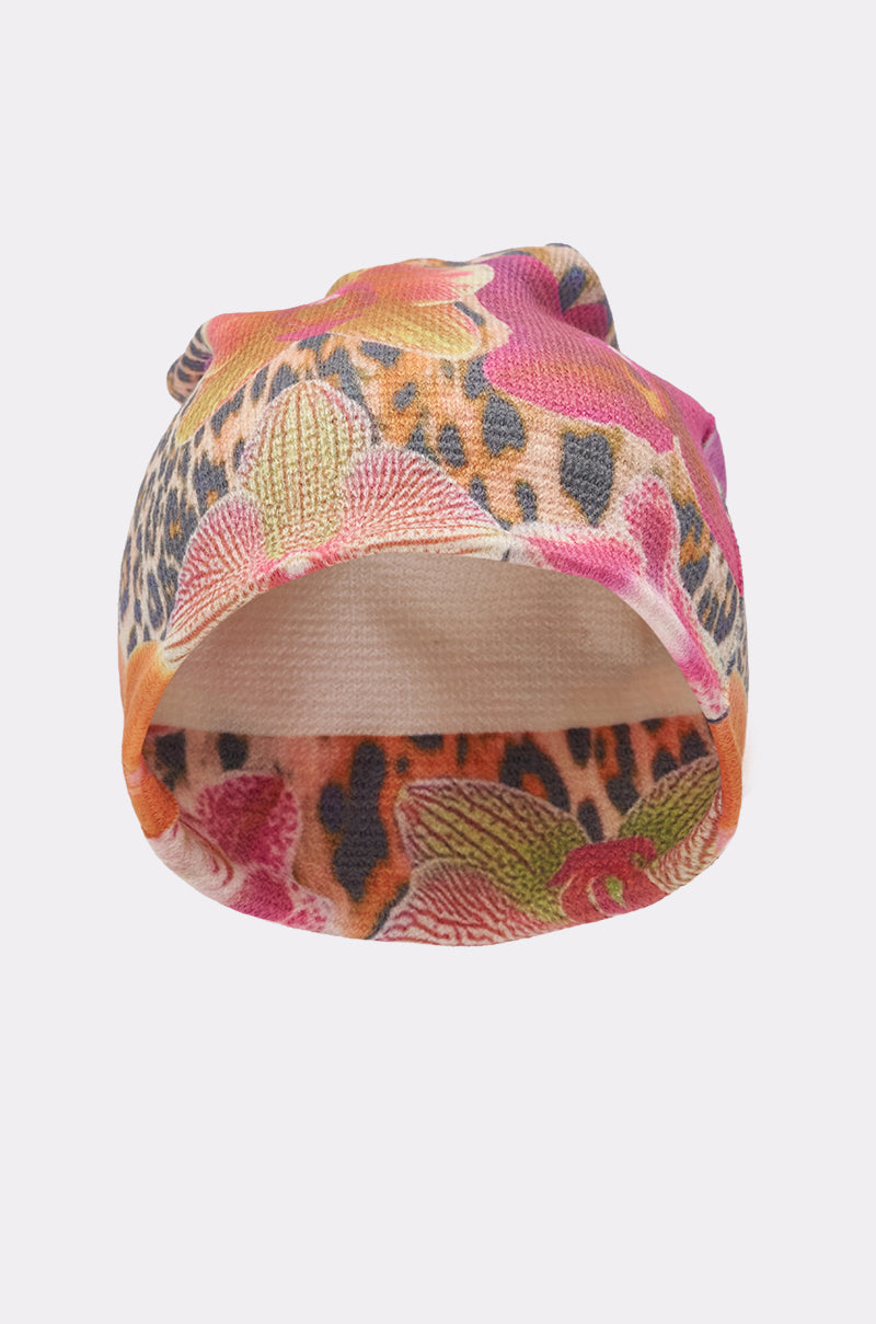 The WILDLY FEMME LIGHTWEIGHT BEANIE features a bold floral leopard print in pink, orange, green, and beige street style, shown with the open end facing forward. 3