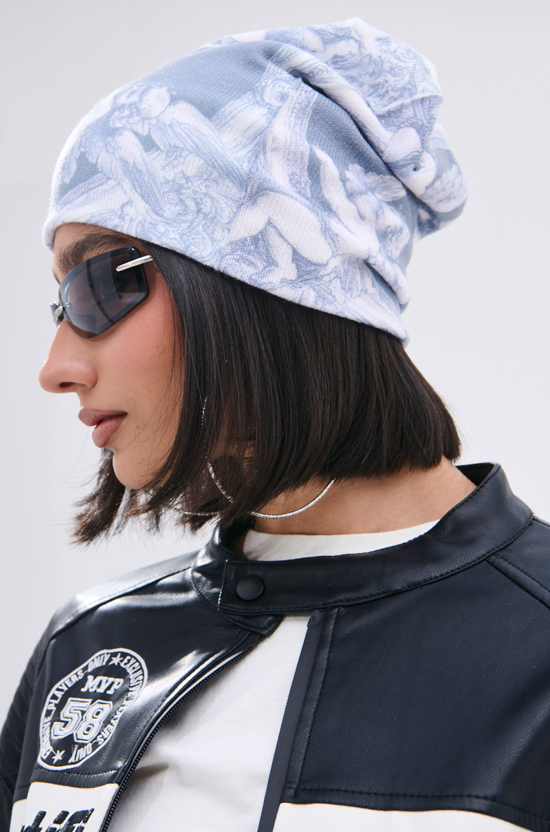 A person with a short bob and dark sunglasses wears the CITY OF ANGELS PRINTED BEANIE, a black and white leather jacket, and a silver hoop necklace—each chic accessory shown in profile against a plain background. 0