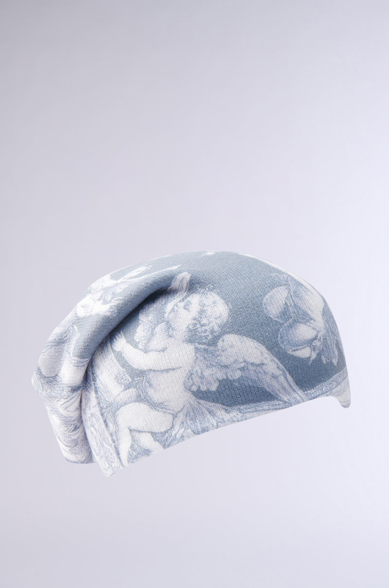 The CITY OF ANGELS PRINTED BEANIE features light blue and white tones with cherub and angel wing graphics, set on a plain background. This stylish accessory adds a whimsical touch to any outfit. 4