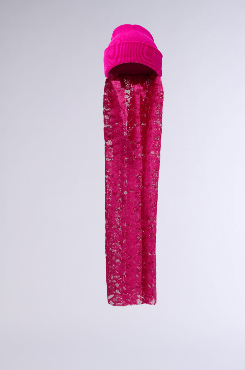 The IN THE CUT LACE VEIL BEANIE in hot pink features a long, translucent lace veil draping elegantly beneath it against a plain light gray background. 1