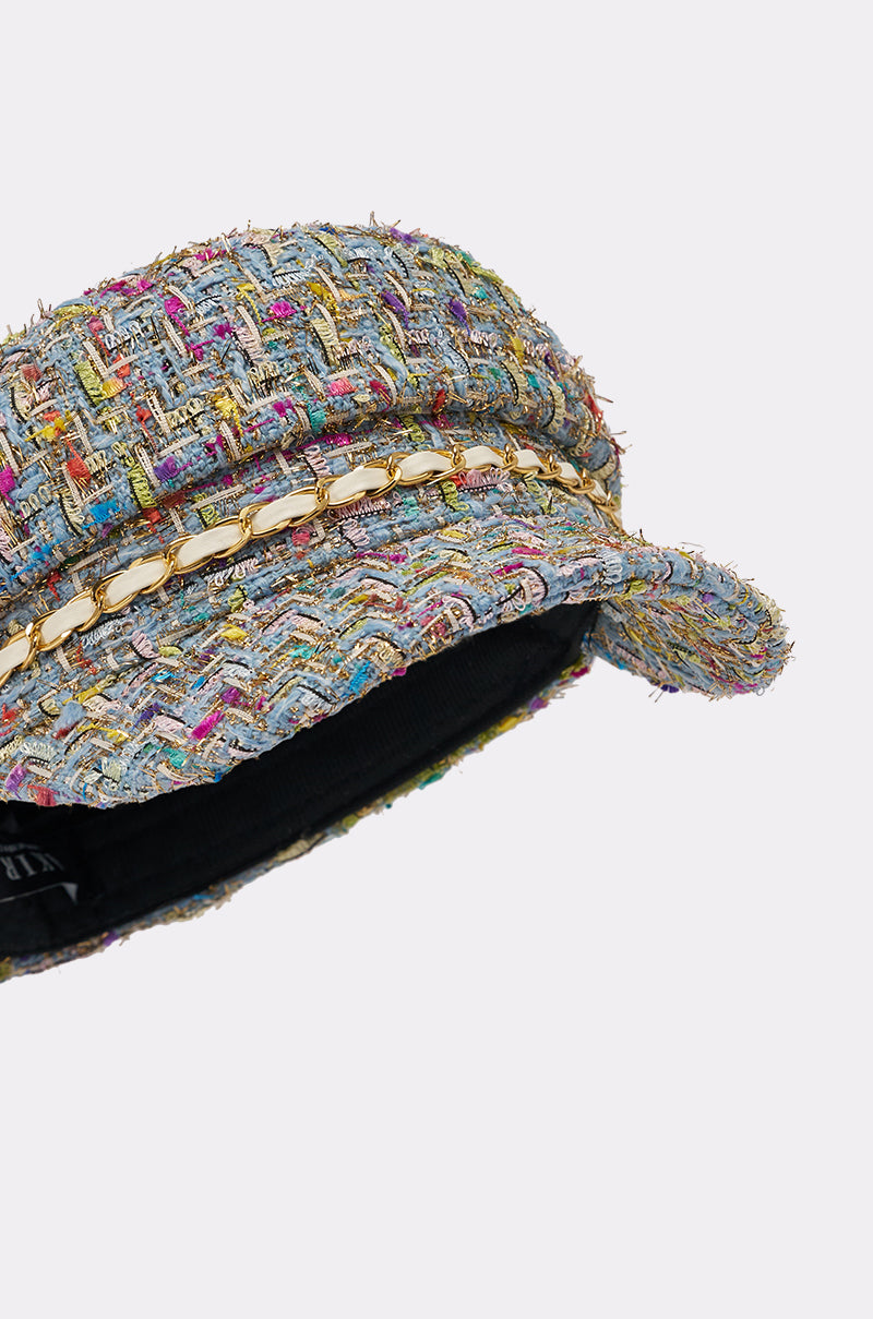 A close-up of the I HAVE CLASS TWEED BRIM HAT, a multicolor newsboy cap with a short brim, featuring a decorative gold chain trim and white woven accents. The richly textured fabric displays a vibrant pattern. 5
