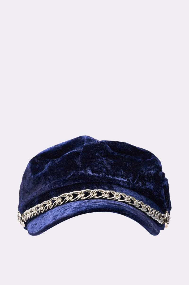The IN THE NIGHT BRIM HAT is a navy blue faux velvet fisherman cap featuring a decorative chain link band across the front, displayed on a plain light background. 1