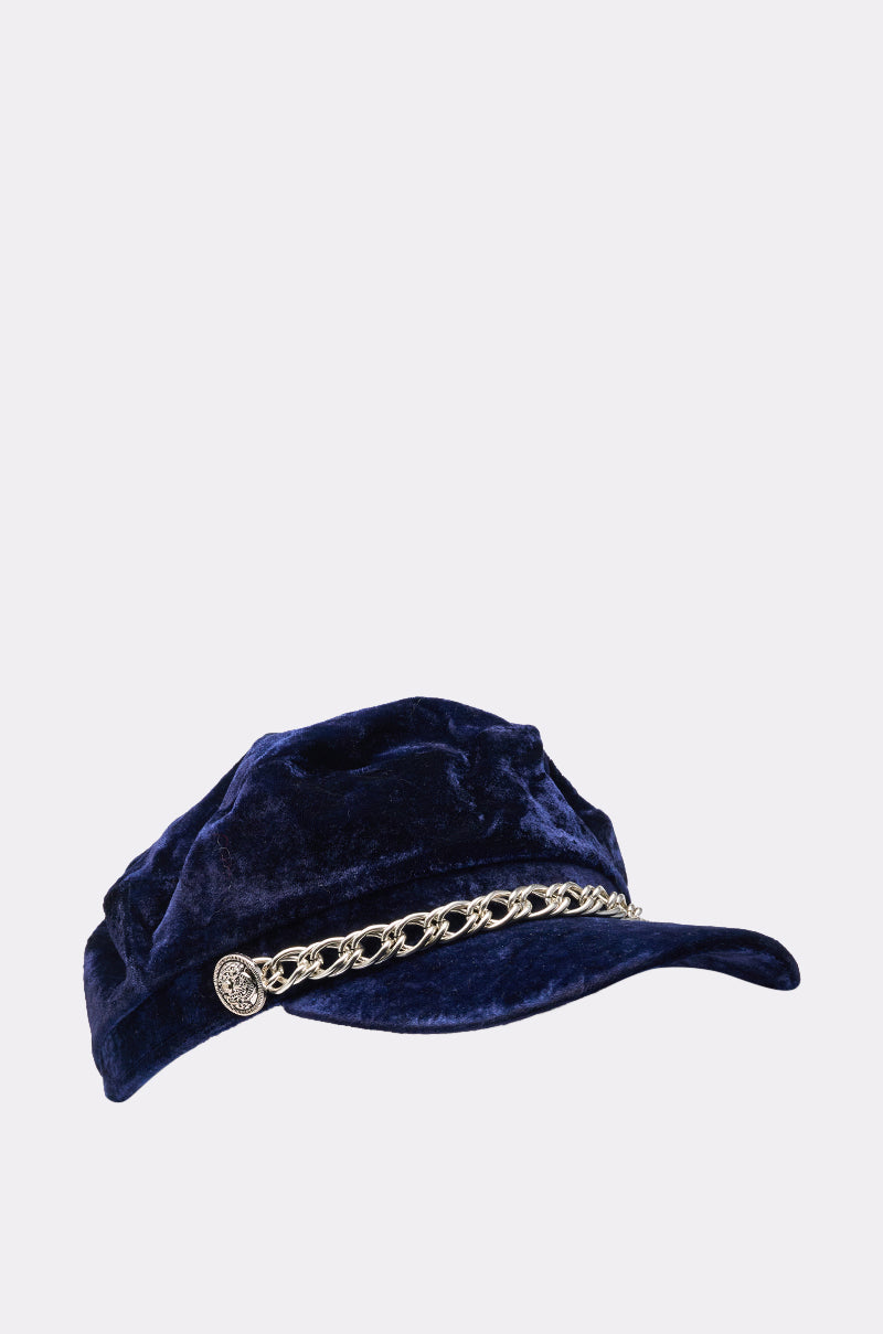 The IN THE NIGHT BRIM HAT is a navy blue faux velvet fisherman cap with a curved brim, detailed with a decorative chain link band and front button accents. 2