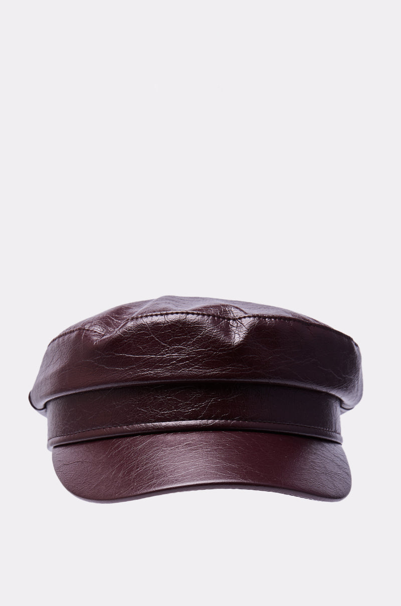 The HERE FOR IT PU BRIM HAT is a structured burgundy faux leather hat with a short, curved visor and banded detailing, shown against a plain light grey background. 2