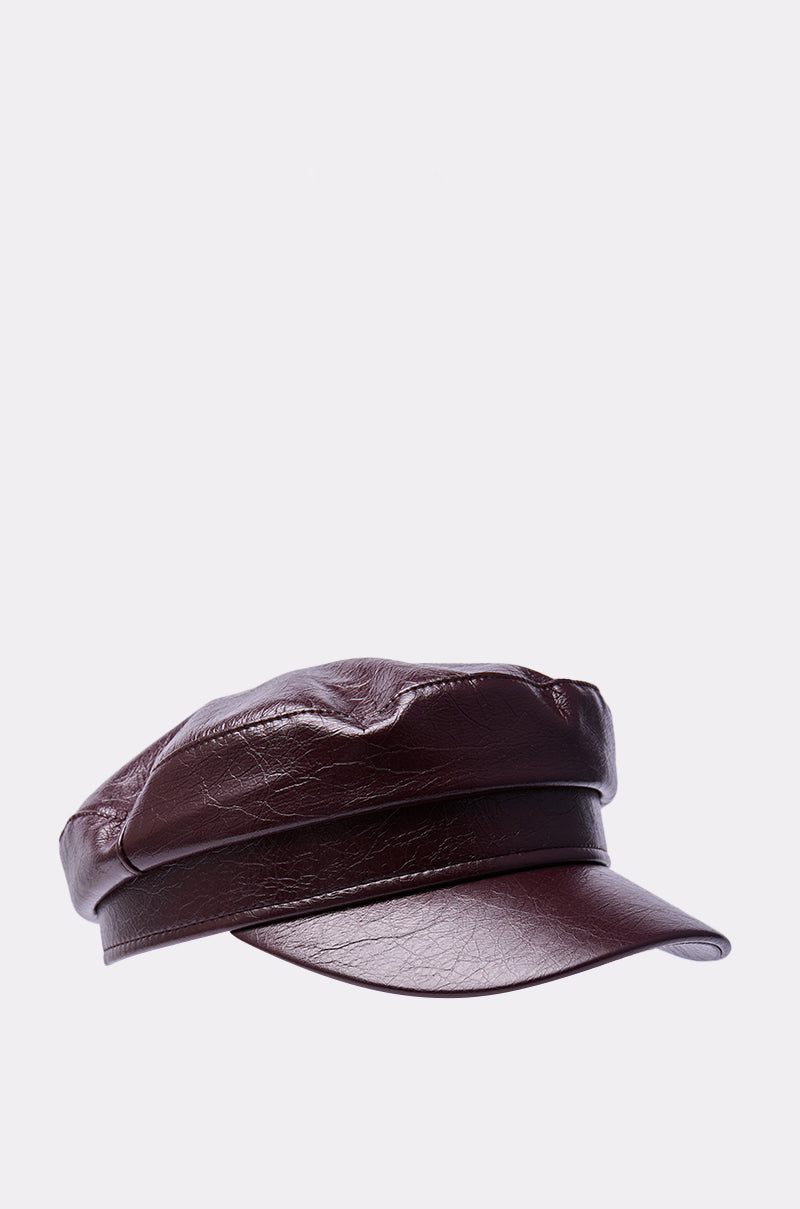 The HERE FOR IT PU BRIM HAT is a structured, dark brown cap with a short, stiff faux leather brim, showcased on a plain light gray background. 3