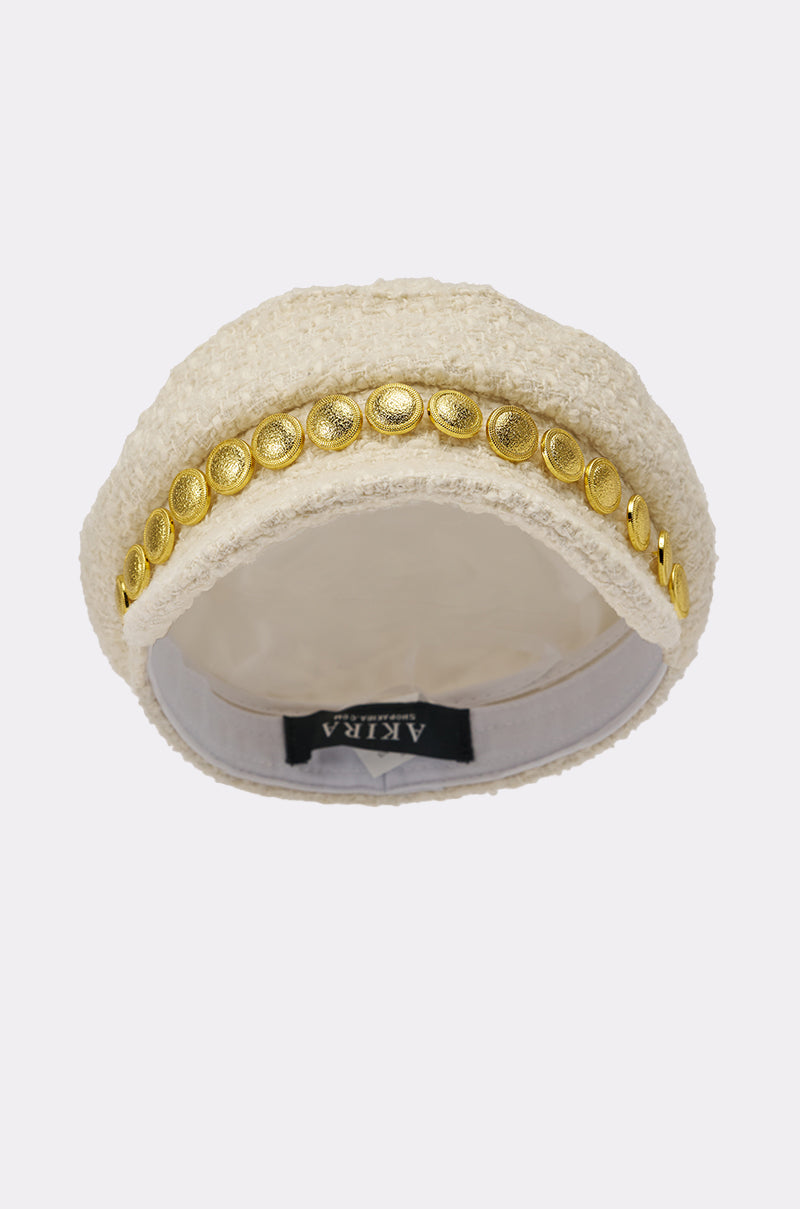 The IN MALLORCA TWEED BRIM HAT features a cream-colored, textured tweed with chic gold coin trim on top and a smooth inner lining with a visible black "AKIRA" label. 3