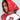 A person wearing a bright red hooded jacket with leopard print lining and a matching RAWR PU HEADSCARF. The jacket displays various patches, including an "R" and "All Star." They look to the side, highlighting their striking profile.