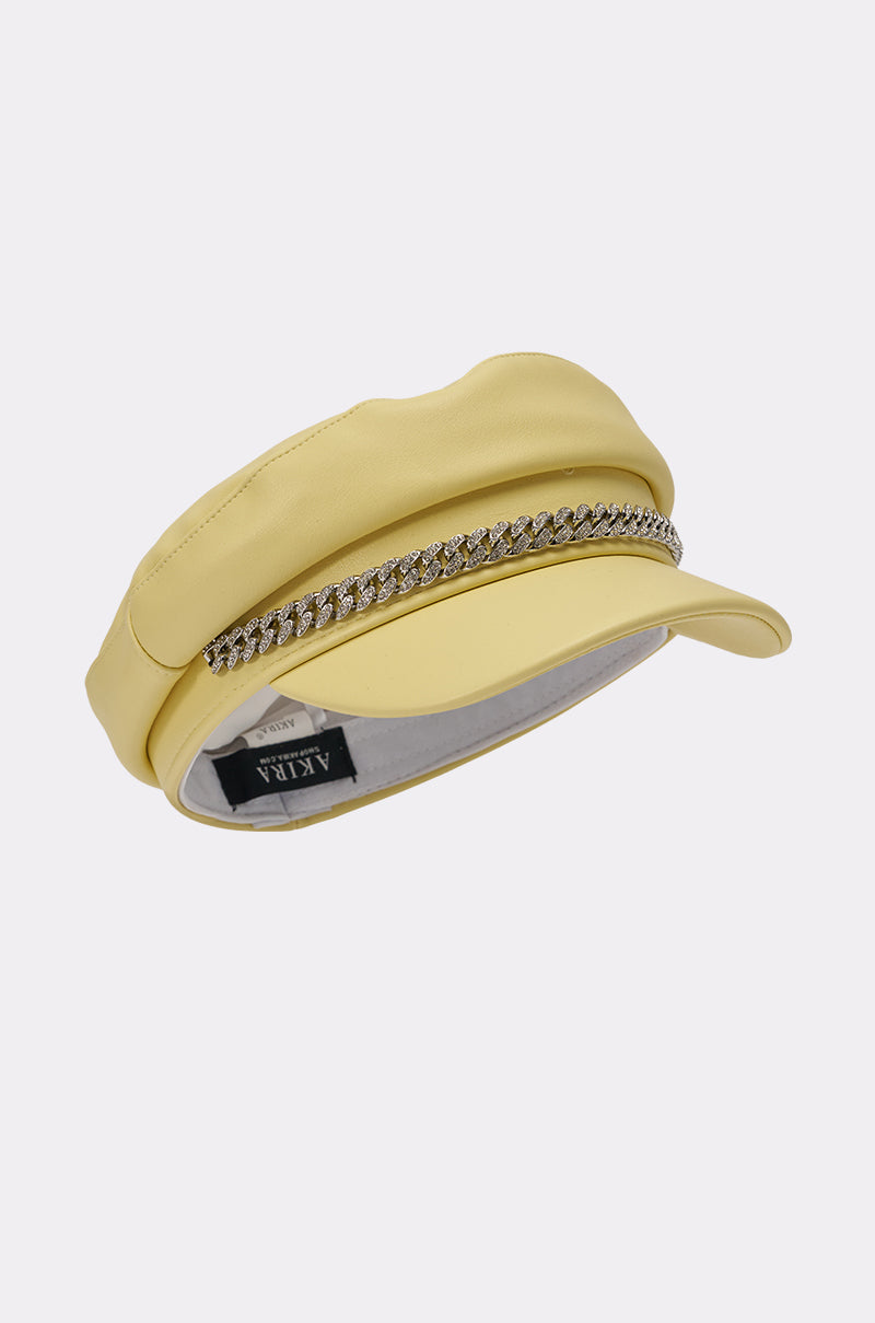 The BUTTER ME UP PU BRIM HAT is a stylish butter yellow faux leather newsboy cap with a rhinestone chain trim and a black "AKILA" label inside the brim. 4
