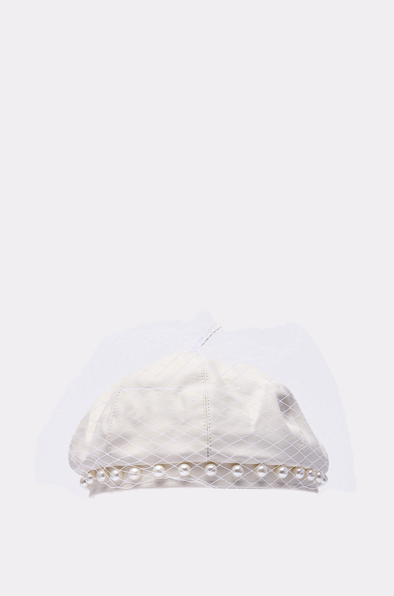 The EDITORIAL BERET is a white beret embellished with pearls, featuring a delicate mesh veil and a pearl-trimmed edge, set against a plain light background.
