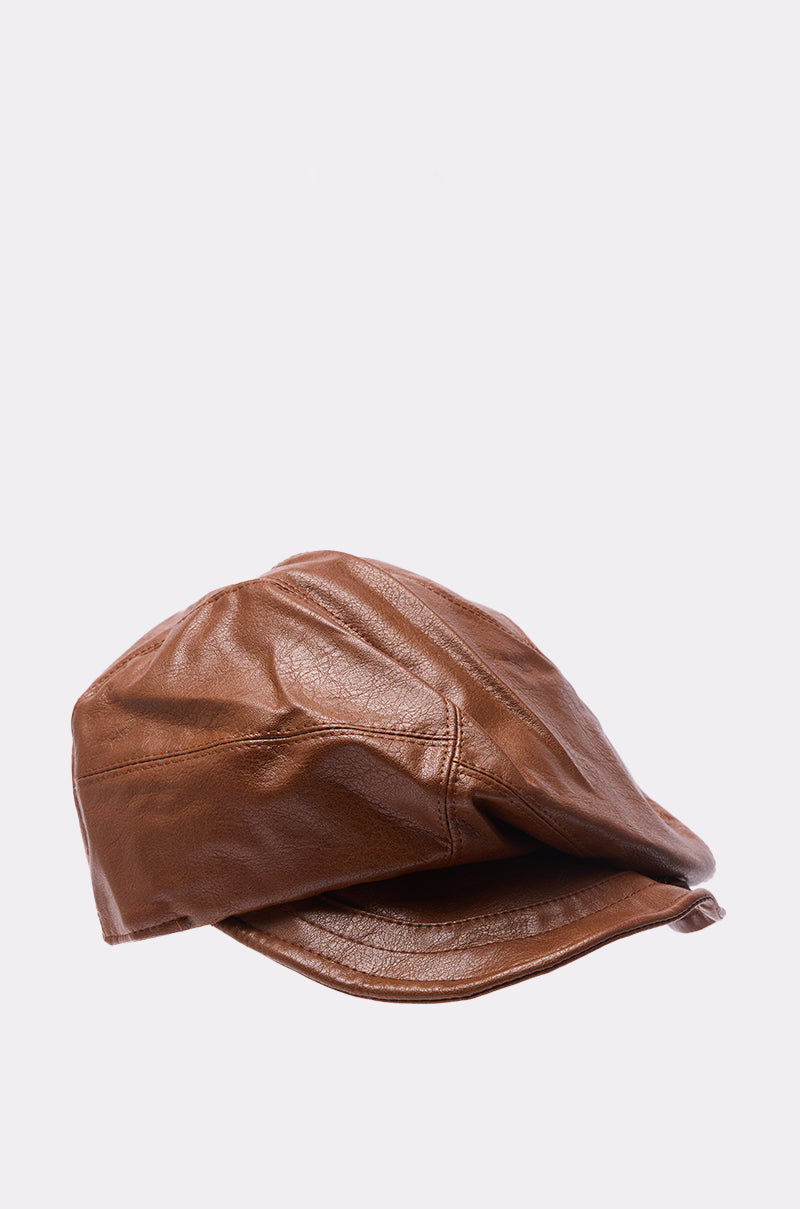 The PULL IT OFF HAT is a brown faux leather newsboy cap with visible stitching, shown on a plain light gray background. This adjustable hat is crafted with care and features the signature AKIRA Label.