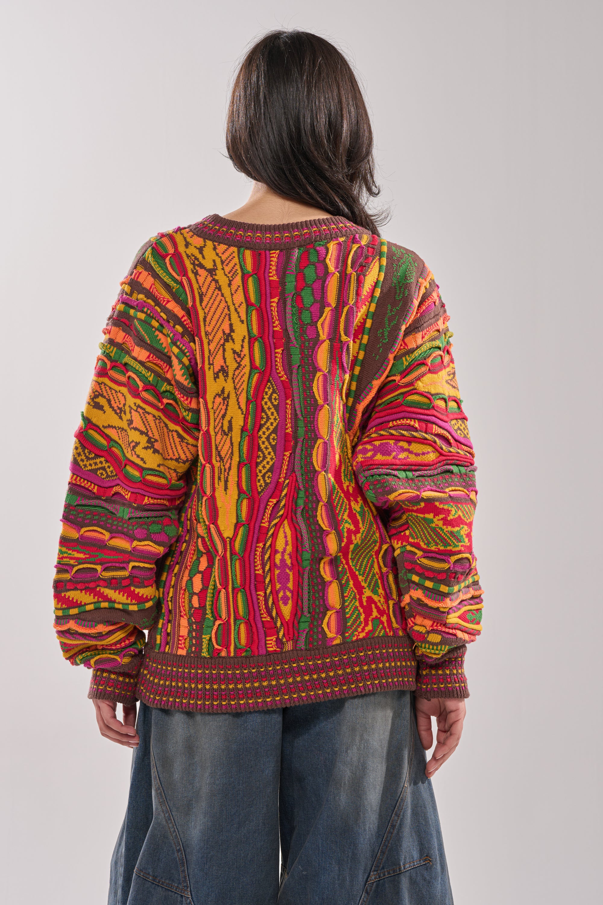 A person with dark hair, seen from behind against a plain light background, wears the THROWBACK SPECIAL KNIT SWEATER with wide-leg blue jeans for a retro-inspired look. 3