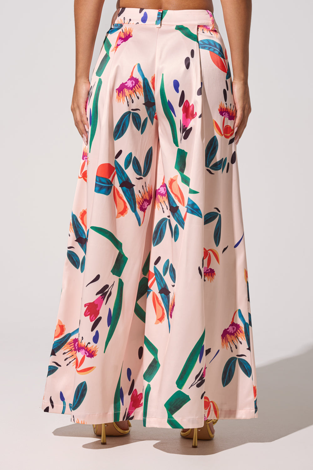 A person is seen from the back in high heels, wearing the CANDY RAIN SATIN WIDE LEG PANT—high-waisted, pink floral satin pants—against a plain background. 5