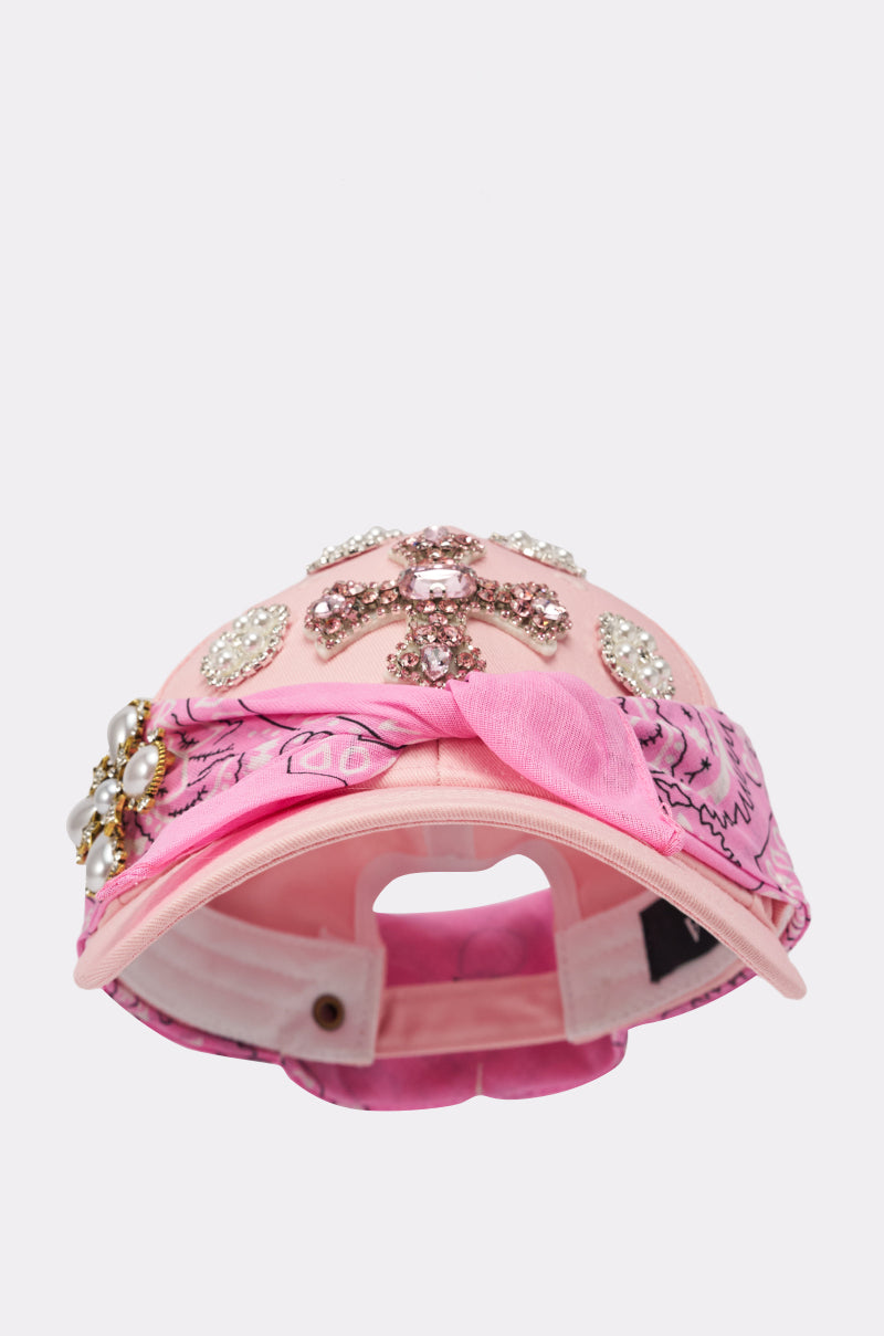 The ASTRA PAISLEY BROOCH HAT is a pink, bedazzled baseball cap featuring rhinestones, pearls, and a pink paisley bandana accent around the brim, displayed front-facing on a white background. 5