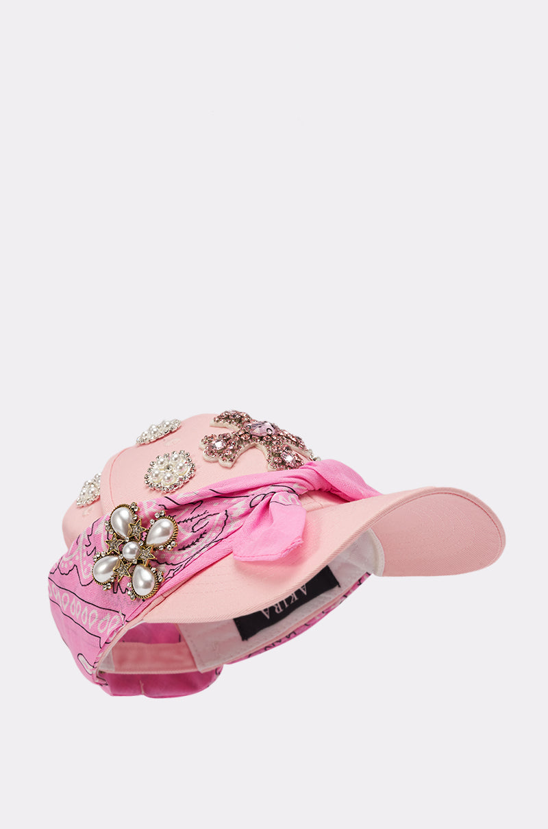 The ASTRA PAISLEY BROOCH HAT is a pink baseball cap featuring jeweled brooches, pearls, a pink paisley bandana accent, curved brim, and visible inner label. 2