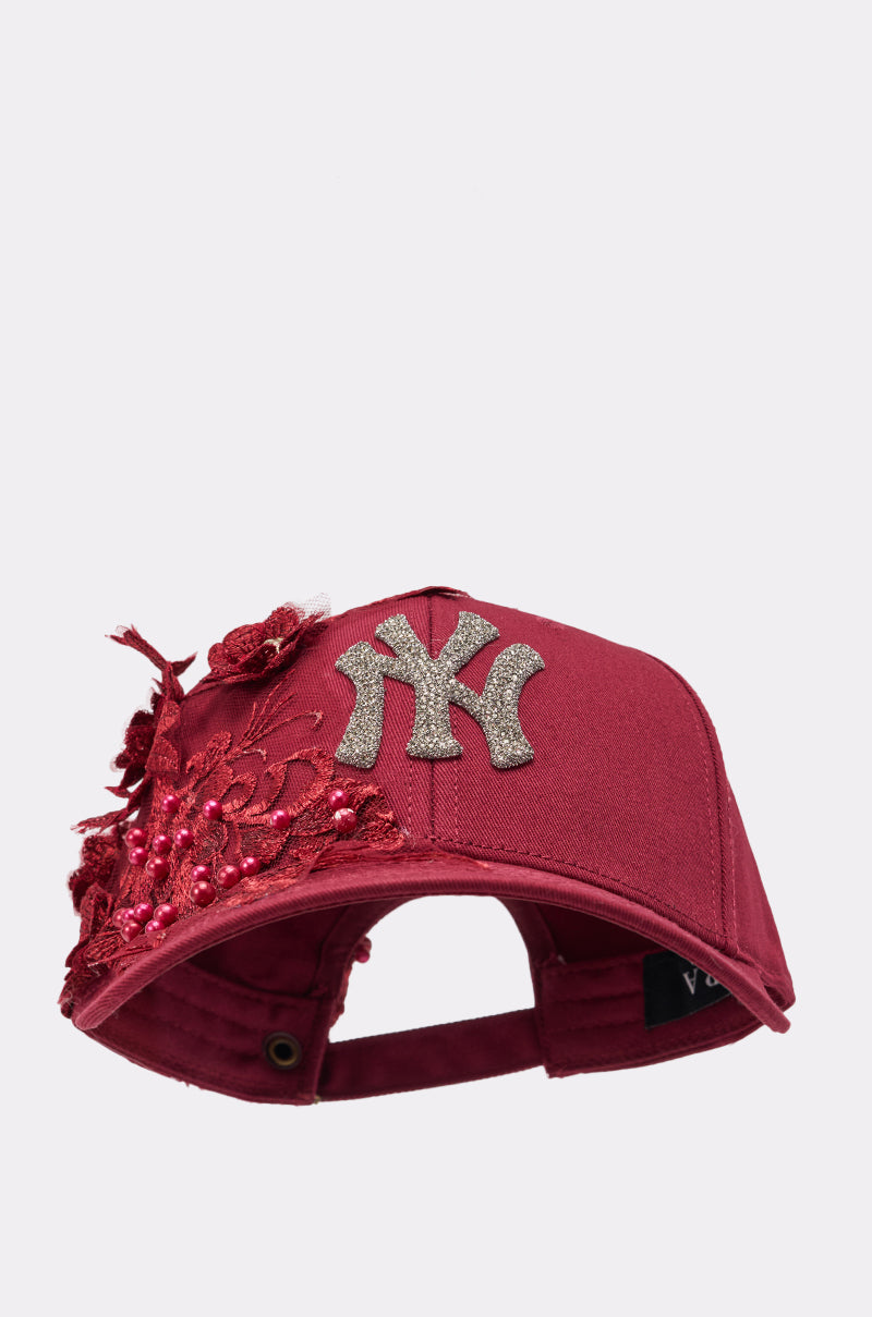 The FROM YA CITY APPLIQUE HAT is a maroon hat with a silver New York Yankees logo on the front, detailed with red sequins, beads, and floral embellishments along one side. 2